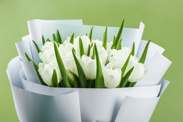Un bouquet de tulipes blanches sur un fond vert pastel fleurissant concept festif