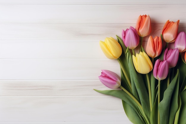 Un bouquet de tulipes colorées sur un fond en bois blanc.