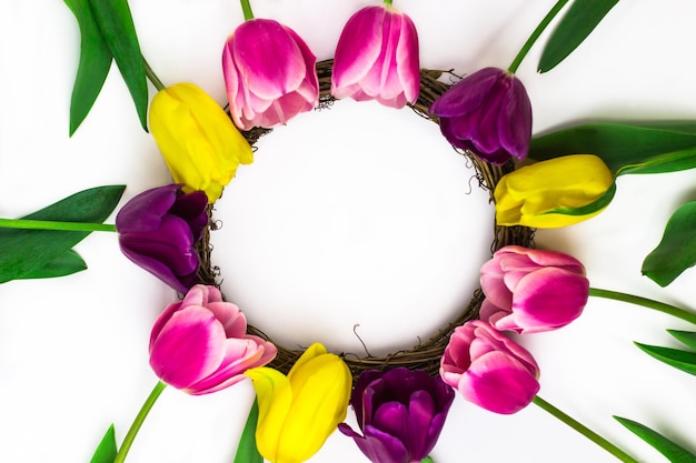 Un bouquet de tulipes de fleurs roses jaunes et violettes formant un cadre pour le texte Vue de dessus Une place pour le texte Fond blanc