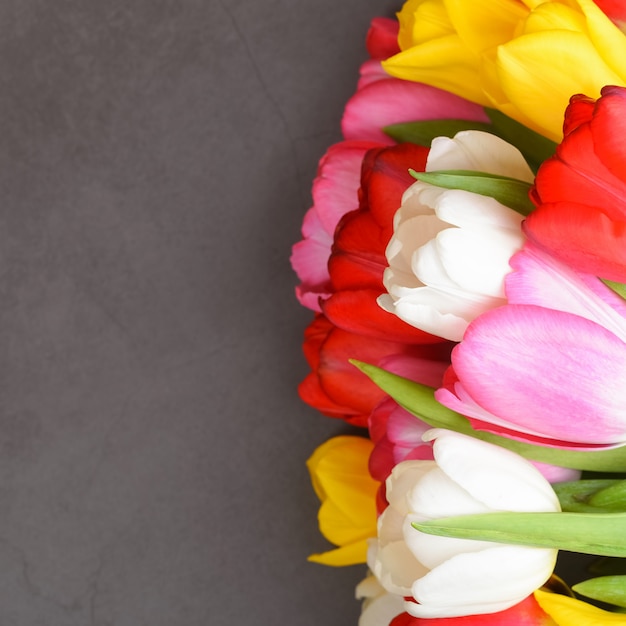 Photo un bouquet de tulipes fraîches, lumineuses et multicolores sur une surface grise