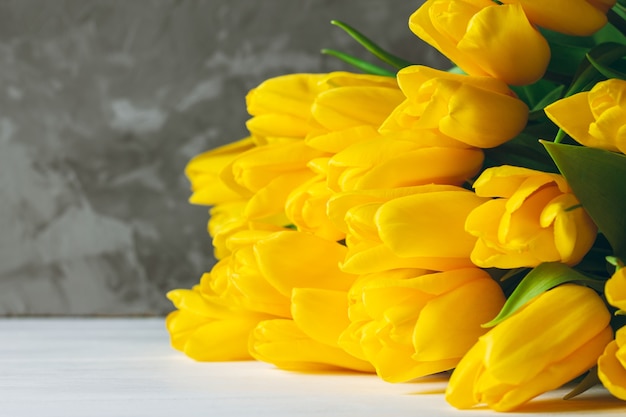 Bouquet de tulipes jaune vif allongé sur une surface en bois blanche