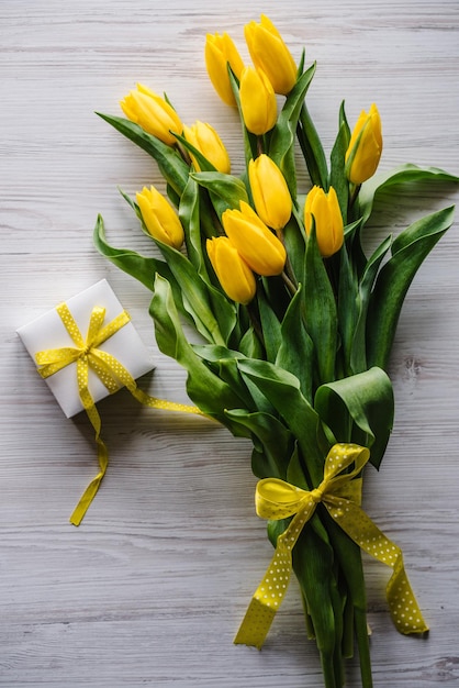 Bouquet de tulipes jaunes avec boîte-cadeau sur fond en bois rustique blanc avec espace pour le message Carte de voeux de vacances pour la Saint-Valentin Fête des mères de la femme Anniversaire de Pâques Vue de dessus mise à plat