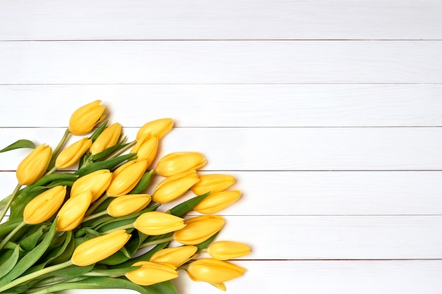 Bouquet de Tulipes jaunes sur un fond en bois blanc.