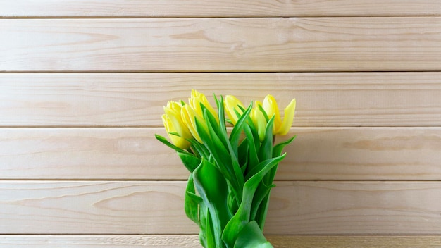 Bouquet de tulipes jaunes sur fond de bois avec espace de copie