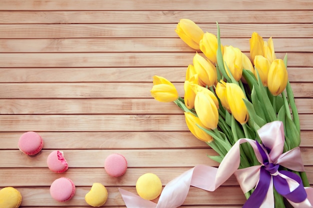 Bouquet de tulipes jaunes avec des macarons sur un fond en bois