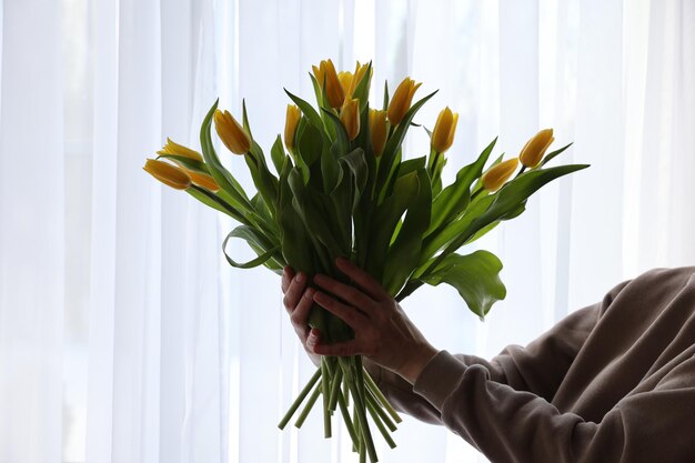 Un bouquet de tulipes jaunes à la main