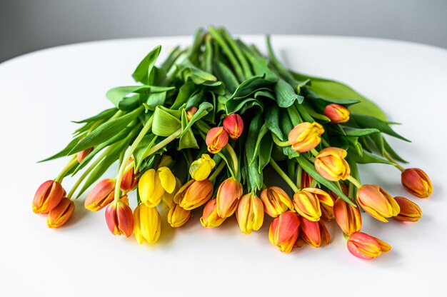 Un bouquet de tulipes jaunes, orange et rouges. Fond blanc. Vue de dessus. Espace copie