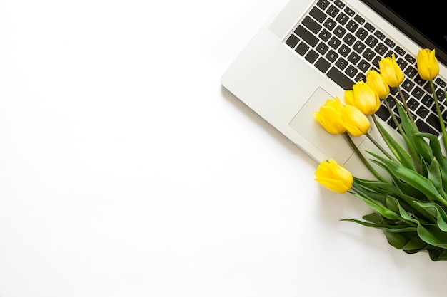 Bouquet de tulipes jaunes et un ordinateur portable sur fond blanc vue de dessus isolée