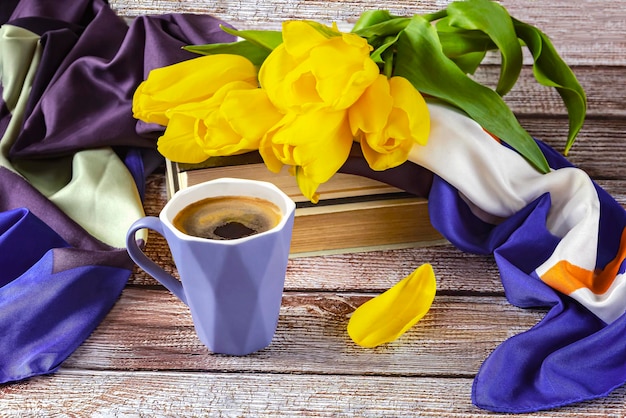 Un bouquet de tulipes jaunes et une tasse de café bleue Printemps nature morte avec un livre