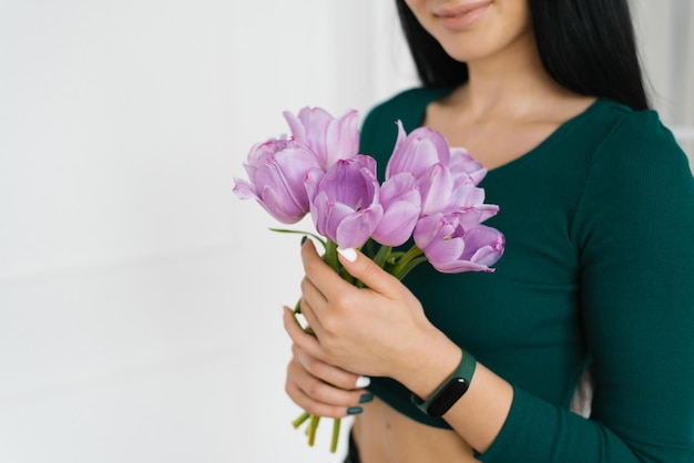 Bouquet de tulipes lilas entre les mains d'une jeune femme en gros plan