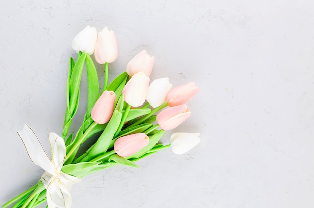 Bouquet de tulipes roses claires sur un béton gris