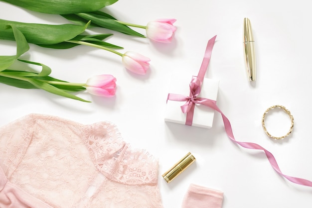 Un bouquet de tulipes roses, un coffret cadeau avec un nœud rose, un chemisier et des cosmétiques. Le concept de Saint Valentin, Fête des Mères, Anniversaire et printemps pour la blogueuse