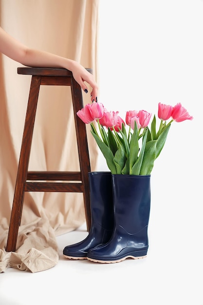 Photo bouquet de tulipes roses dans une botte en caoutchouc bleu