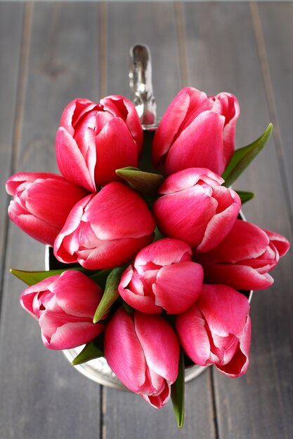 Bouquet de tulipes roses dans un vase en métal sur fond en bois