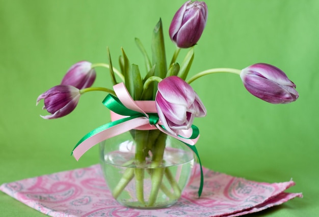 Bouquet de tulipes roses dans un vase transparent sur fond vert