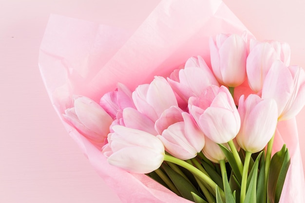 Bouquet de tulipes roses enveloppé dans du papier rose.