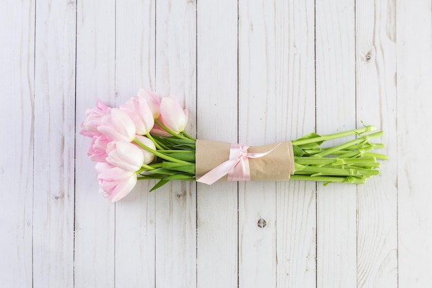 Bouquet de tulipes roses sur fond de bois.