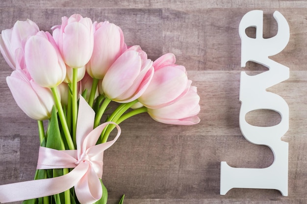 Bouquet de tulipes roses sur fond de bois.