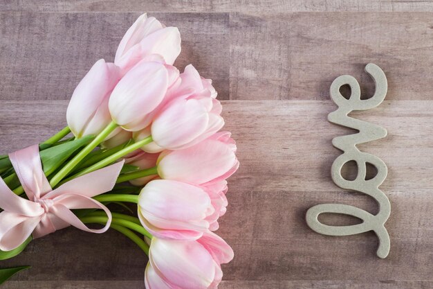 Bouquet de tulipes roses sur fond de bois.