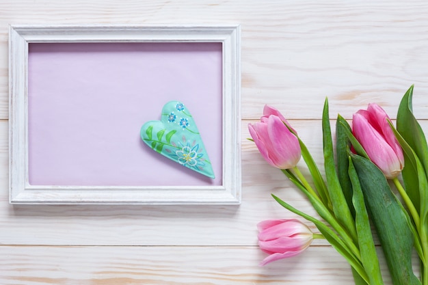 Bouquet de tulipes roses et lieu pour texte avec coeur dans cadre blanc en bois