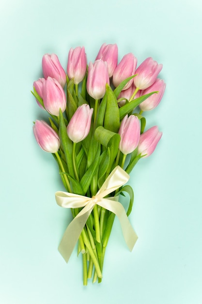 Bouquet de tulipes roses avec ruban de satin sur fond bleu Fête des Mères Pâques Saint Valentin