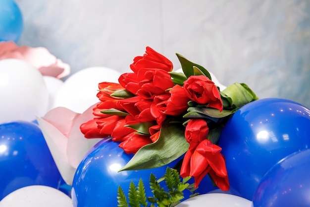 Bouquet de tulipes rouges allongé sur des ballons bleus et blancs