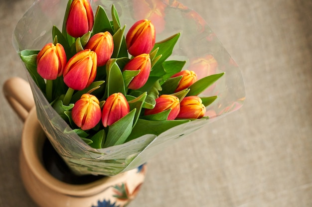 Bouquet de tulipes rouges dans une cruche sur marron