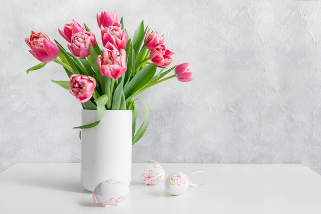Bouquet de tulipes rouges dans un vase sur une table blanche vintage