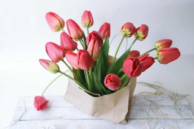 Bouquet de tulipes rouges en fleurs dans un sac en papier sur un fond blanc fleurs de printemps