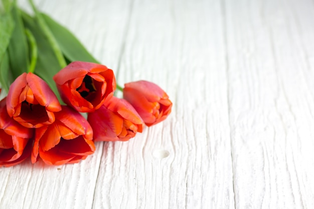 Un bouquet de tulipes rouges sur une table en bois blanche.