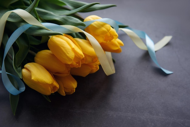 Bouquet de tulipes avec ruban bleu et jaune sur fond noir