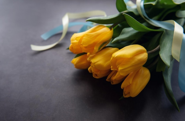 Bouquet de tulipes avec ruban bleu et jaune sur fond noir