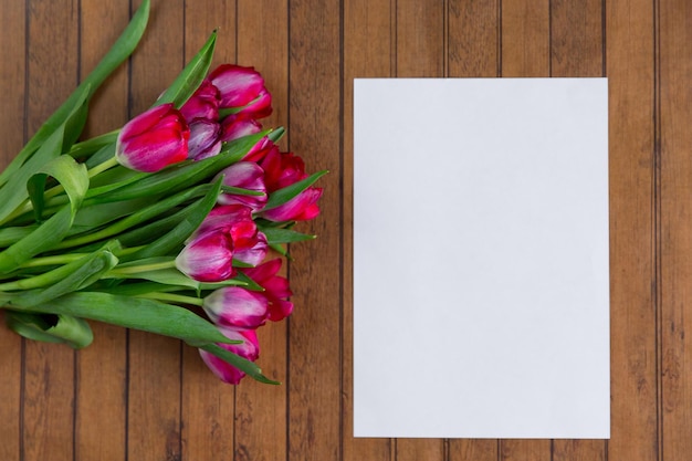 Bouquet de tulipes sur table en bois feuille de papier blanc