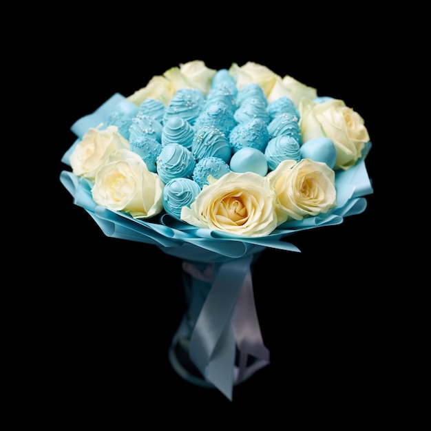 Bouquet unique de roses blanches et de fraises mûres recouvertes de chocolat bleu se dresse dans un vase sur fond noir