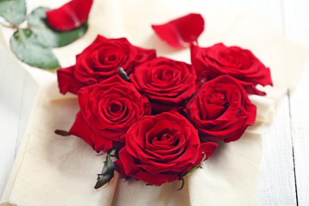 Bourgeons de roses rouges fraîches en forme de coeur avec toile de lin sur fond de bois