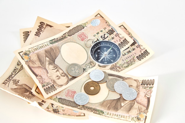 Photo boussole avec des billets de yen japonais et pièce de yen japonais sur fond blanc