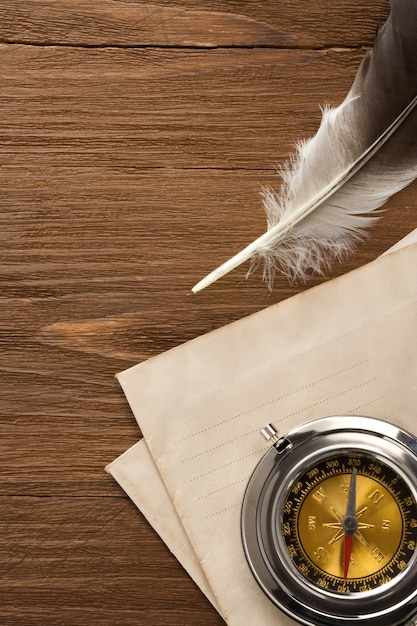 Boussole et plume d'encre à l'enveloppe sur la texture du bois vintage