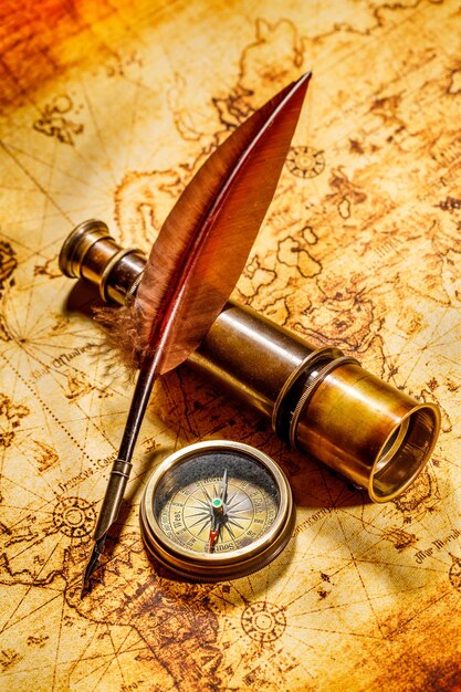 Boussole vintage, plume d'oie et spyglass allongé sur une vieille carte.