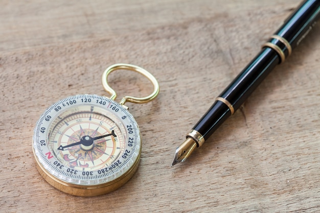 boussole vintage et un stylo sur le plancher de bois