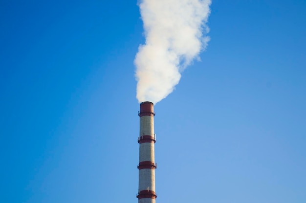 Bout du tuyau avec de la fumée sur un ciel bleu