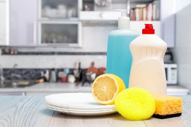 Bouteille d'assiettes d'éponges liquides vaisselle et citron sur fond bleu