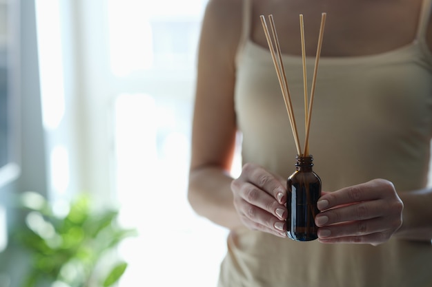 Bouteille avec des bâtons d'encens dans des mains féminines. Concept de médecine orientale et de relaxation