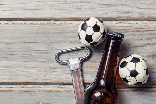 Bouteille de bière avec des ballons de football sur un fond en bois