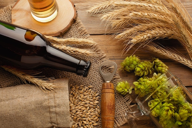 Une bouteille de bière avec des épillets de blé d'avoine de houblon vert et des verres avec de la bière sombre et claire sur un tableau noir rayé Vue de dessus