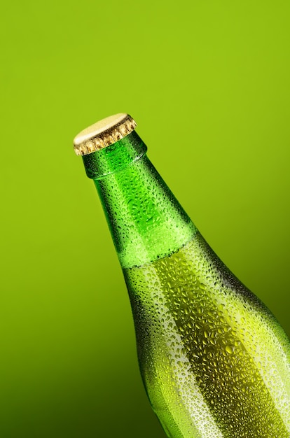 Bouteille de bière avec des gouttes d'eau sur fond vert