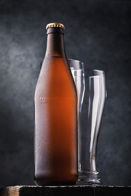 Bouteille de bière légère et deux verres vides sur une table en bois