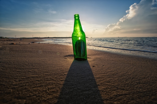 Bouteille de bière sur une plage de sable avec ciel clair