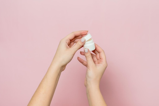 Bouteille blanche ou bouteille avec pommade à la crème dans les mains de la femme Bouteille de soins du visage avec produit cosmétique