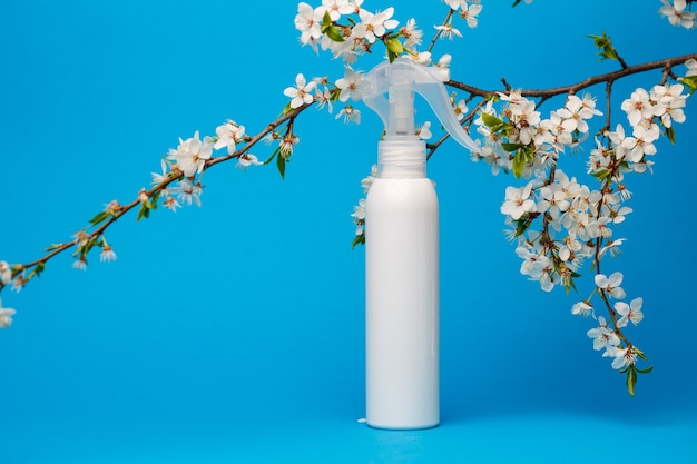 bouteille blanche avec crème, shampoing pour cheveux, gel douche, fond bleu isolé, beauté et jeunesse du corps humain, arbre fleuri