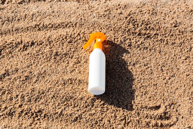 Bouteille blanche de lotion de bronzage sur le sable avec l'espace de copie. crème solaire spf sur la plage de la mer dans le concept de vacances d'été.